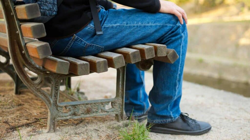 Picture of a person resting on a public bench after a total knee replacement