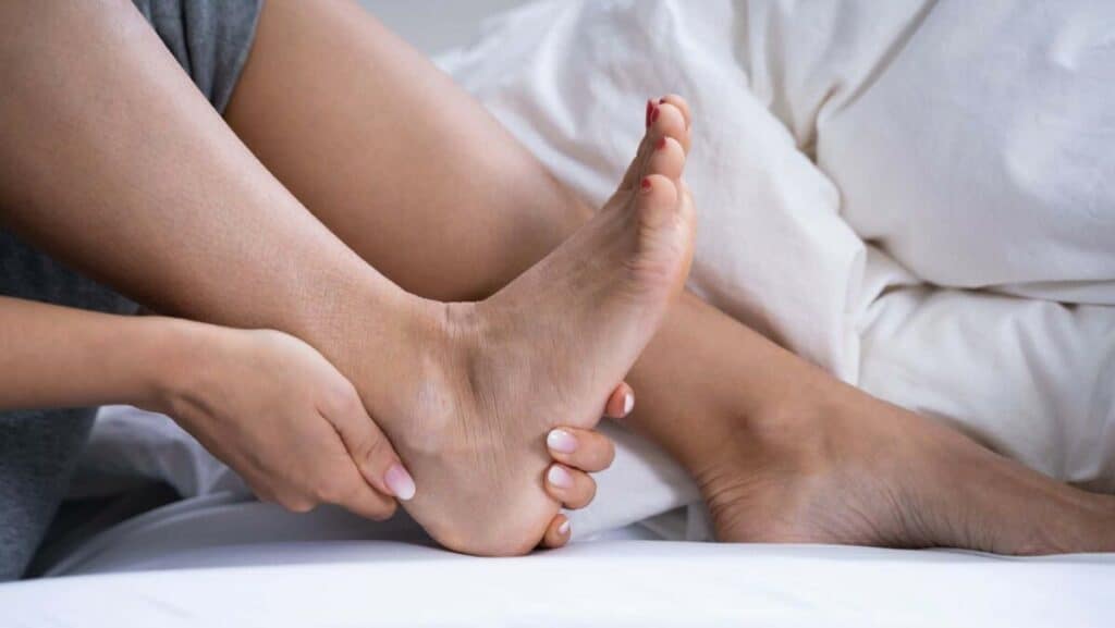 Picture of someone holding a painful heel in bed