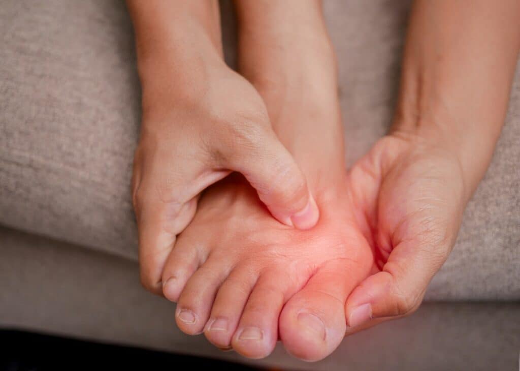 Person holding a painful bone spur on top of their foot